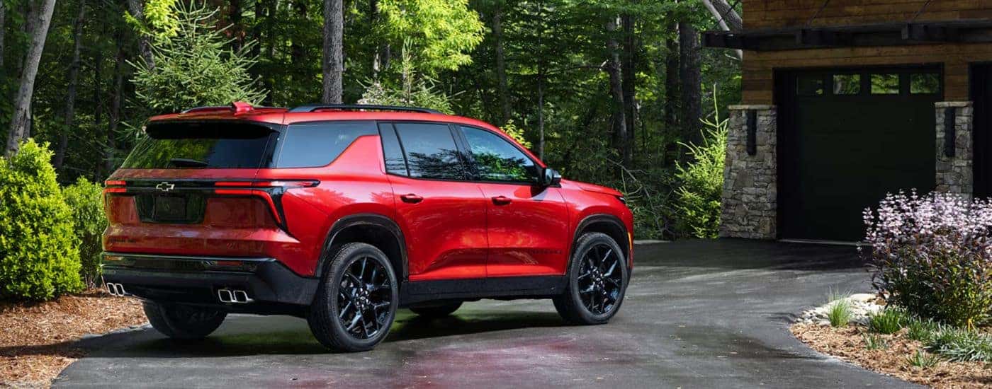 A rear-facing red 2026 Chevy Traverse parked in front of a garage.