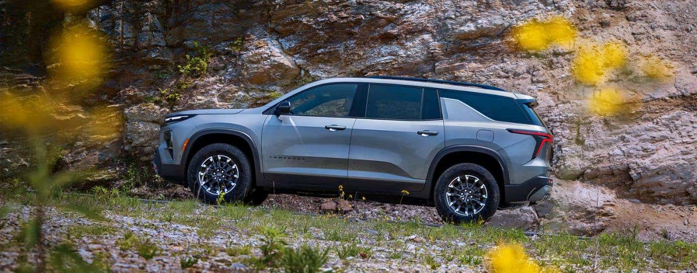 A gray 2026 Chevy Traverse shown driving a rocky dirt road.