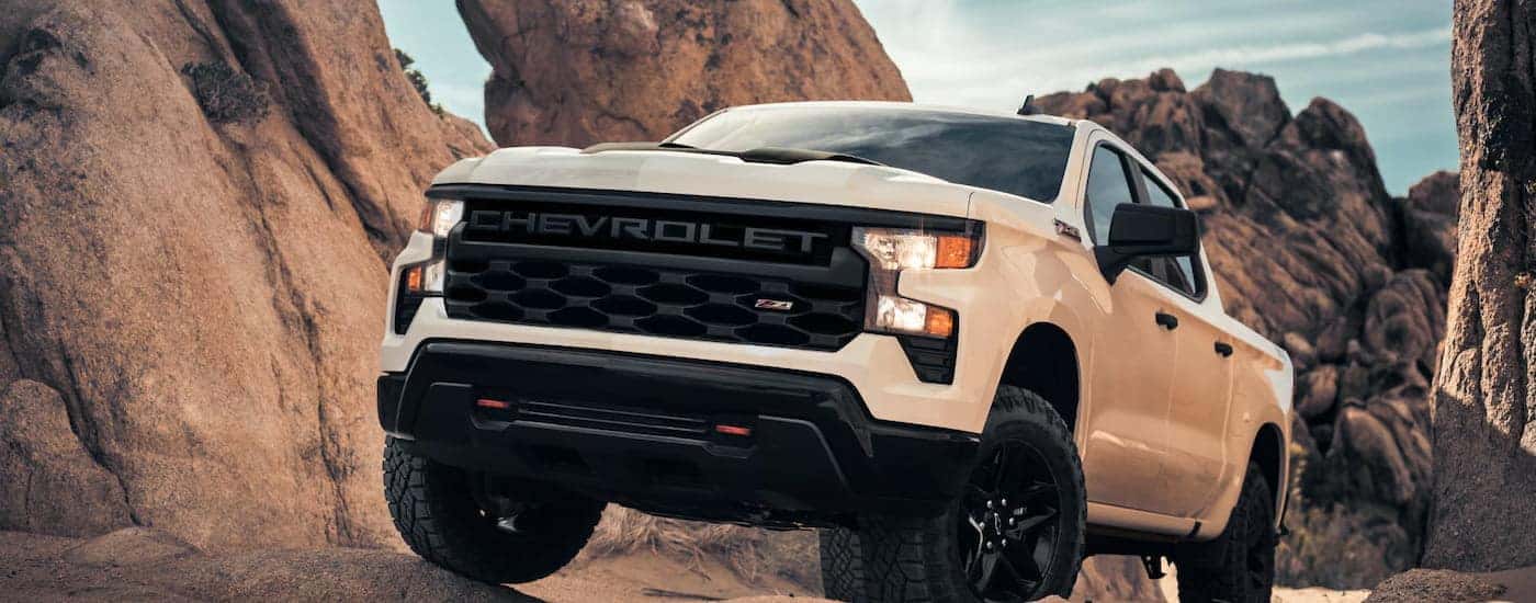 White 2026 Chevy Silverado 1500 Z71 driving off-road up a hill.