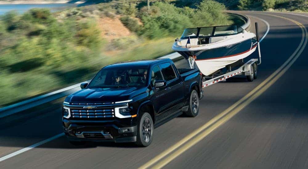 A black 2027 Chevy Silverado 1500 High Country towing a boat.