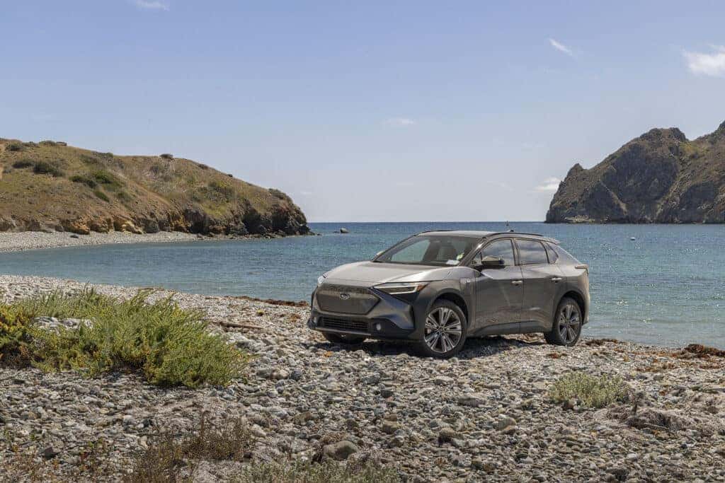 2024 Grey Subaru Solterra Parked Front 3/4 View on a Rocky Beach Near Water