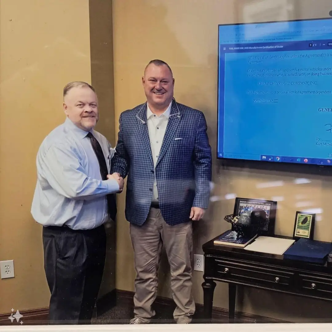 Two men shaking hands in front of TV screen