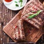 Steak, tomatoes, mushrooms, and sauce on wood table
