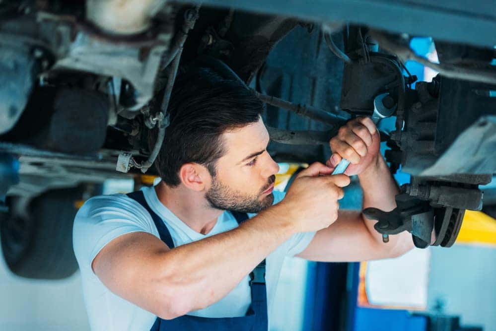 Auto mechanic performing work under car