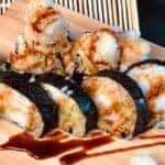 Sushi rolls served on wooden plate with sauce
