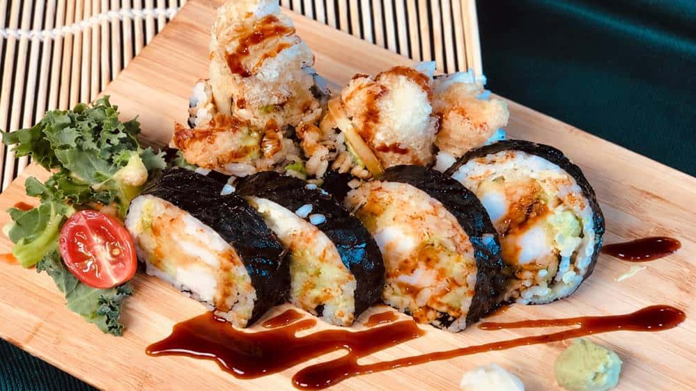 Sushi rolls served on wooden plate with sauce