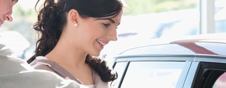 Car dealer pointing the interior of a car