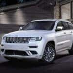 White Jeep Grand Cherokee parked on a driveway at night