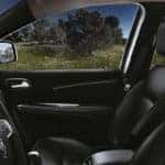 Side view of 2019 Dodge Journey front seats driving past trees
