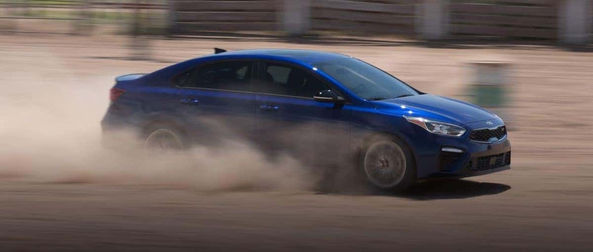 New Blue Kia Forte Racing Down Desert Road