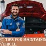 A mechanic standing in front of a car and smiling