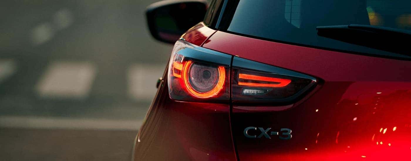 A close-up shows the driver side taillight on a red 2021 Mazda CX-3.