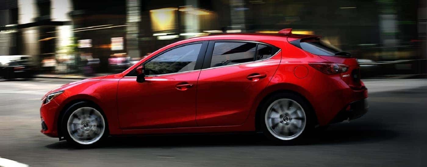 A red 2014 Mazda3 is shown from the side.
