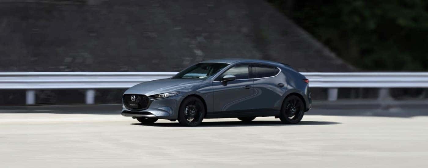 A grey 2025 Mazda3 is shown driving to a Mazda dealer near Vernon.
