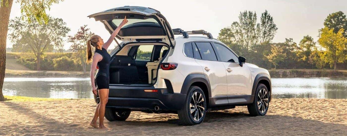 A white 2025 Mazda CX-50 Hybrid is parked on a lakeshore.