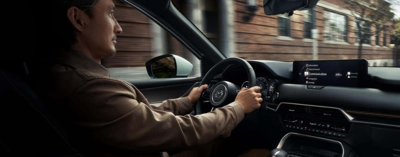 A person is shown driving a 2025 Mazda CX-90 for sale.