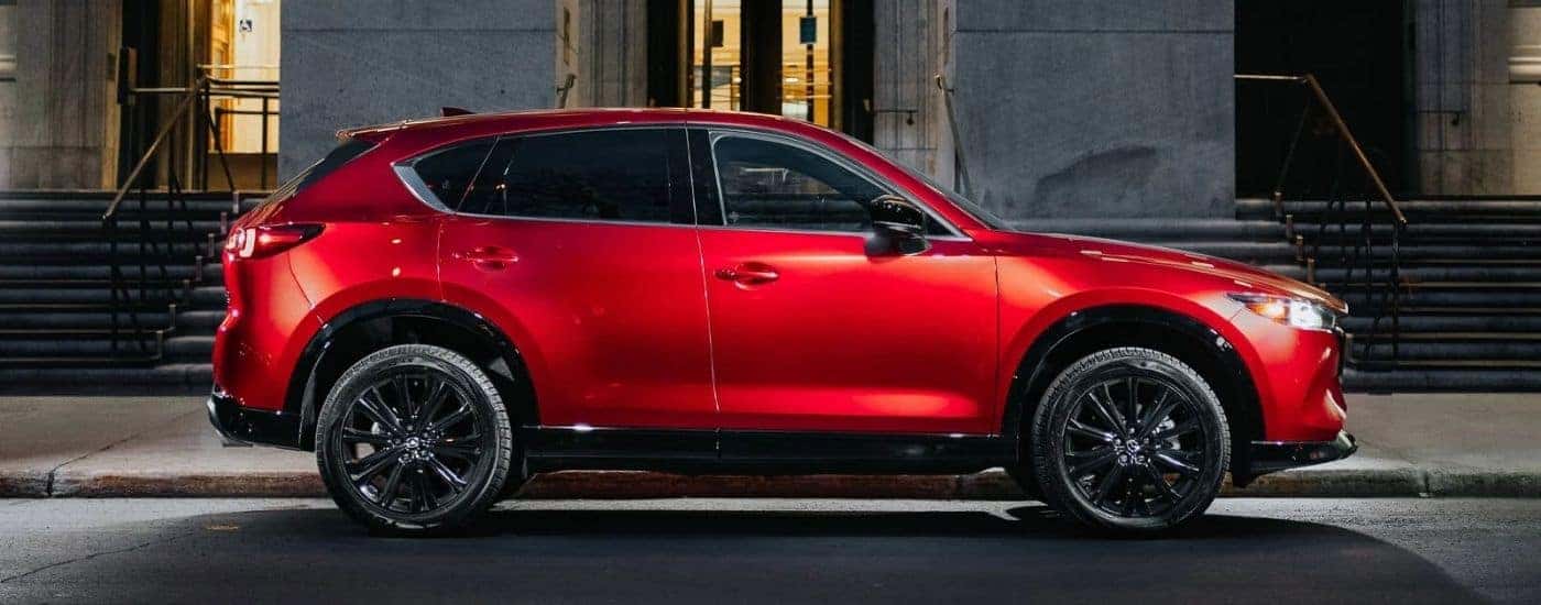 A red 2025 Mazda CX-5 parked in front of a building.