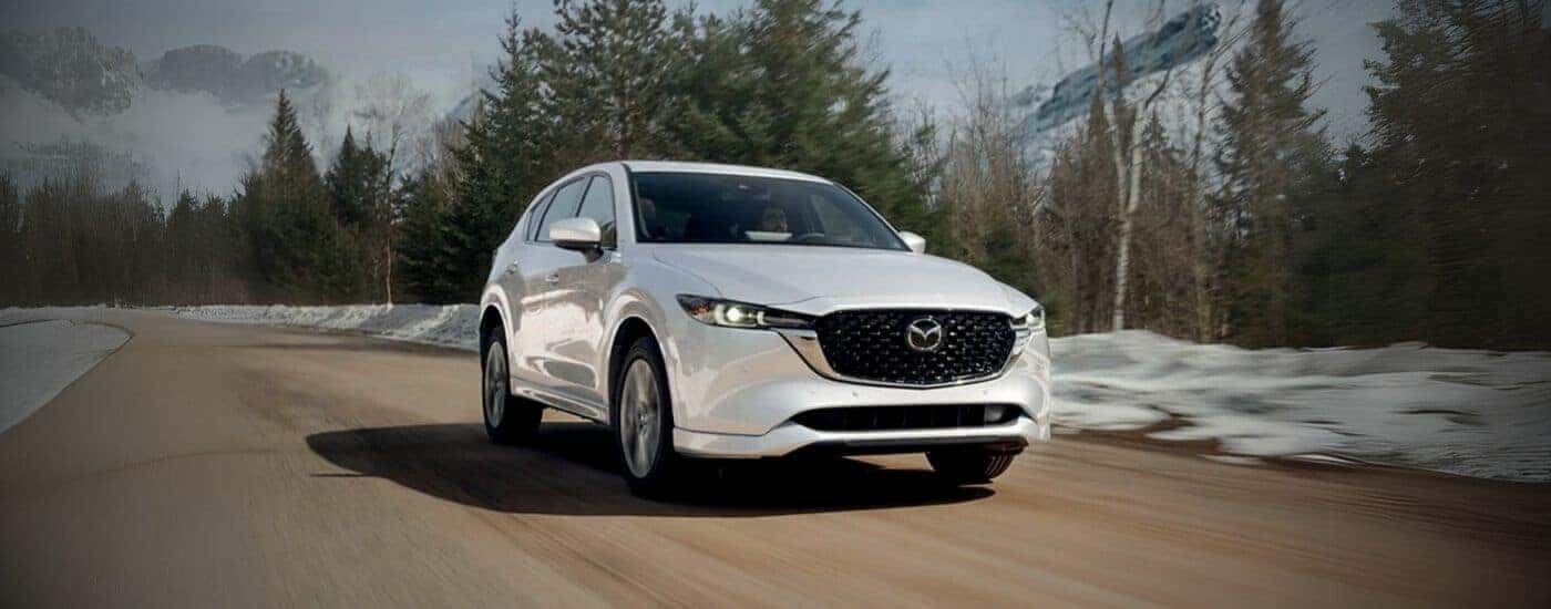 A white 2025 Mazda CX-5 driving on a dirt trail.