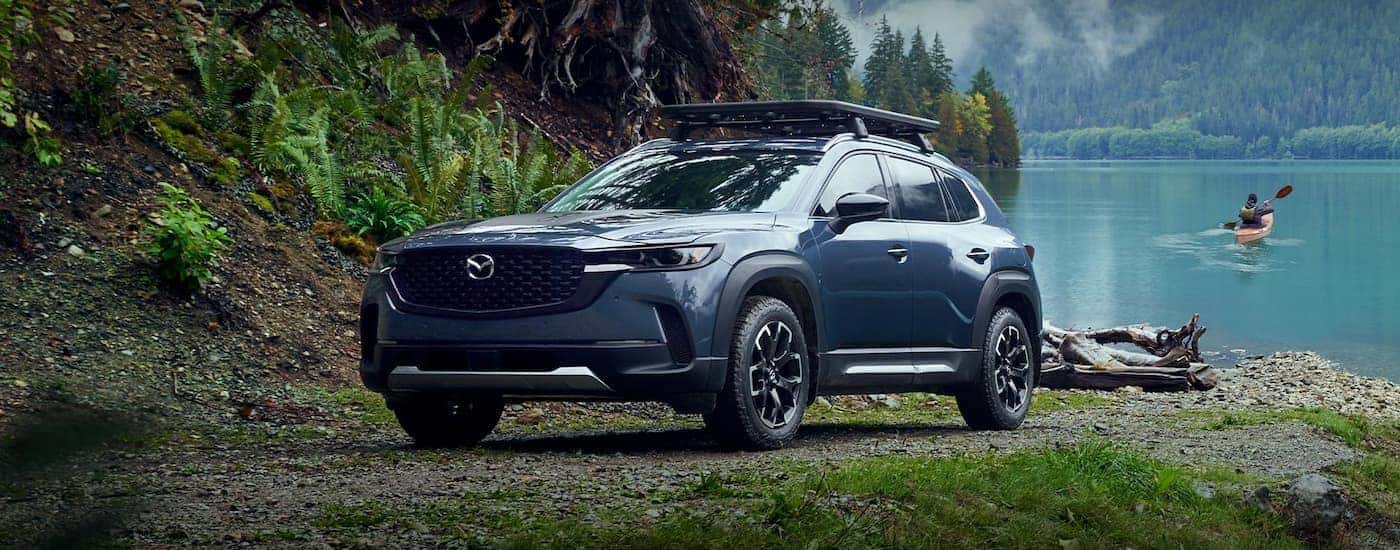 A blue 2023 Mazda CX-50 parked near a lake.