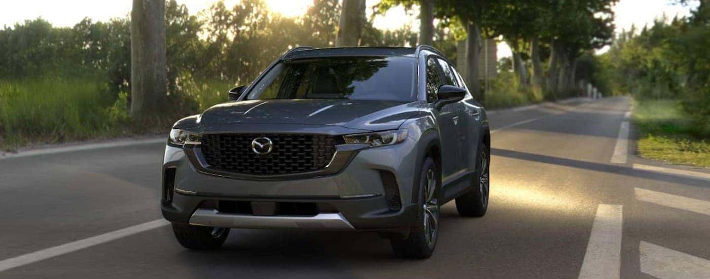 Gray 2025 Mazda CX-50 driving down a rural road