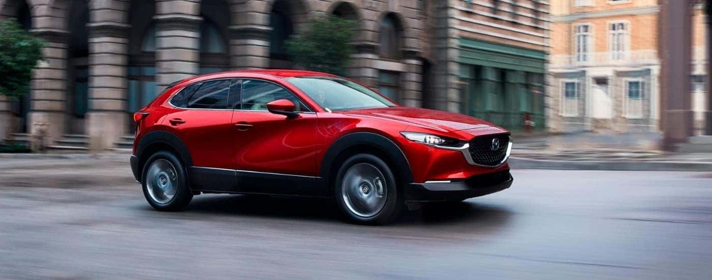 A red 2020 Mazda CX-30 is shown driving to a Mazda dealer near East Hartford.
