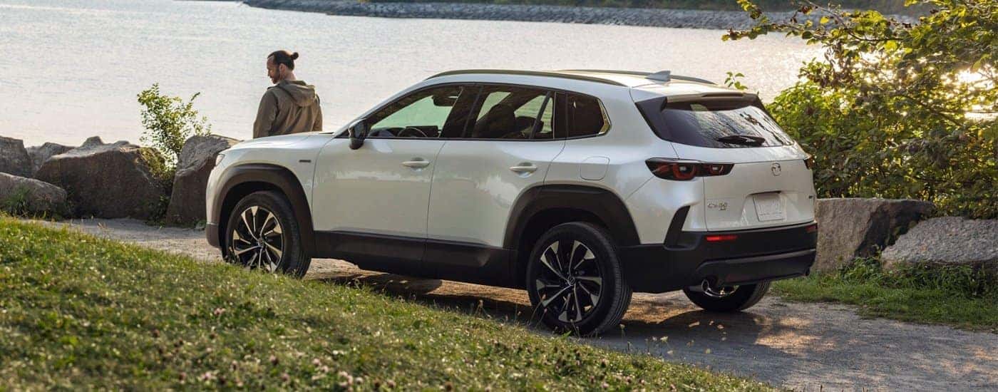 A white 2025 Mazda CX-50 Hybrid is shown next to a river.