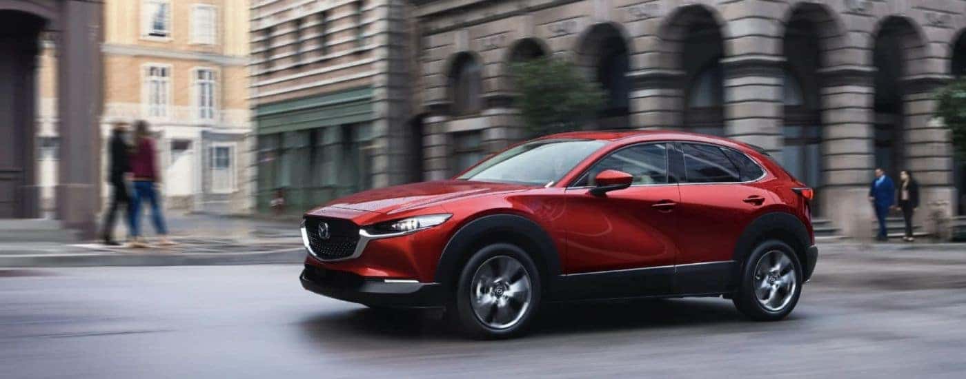 A red 2025 Mazda CX-30 driving on a city street