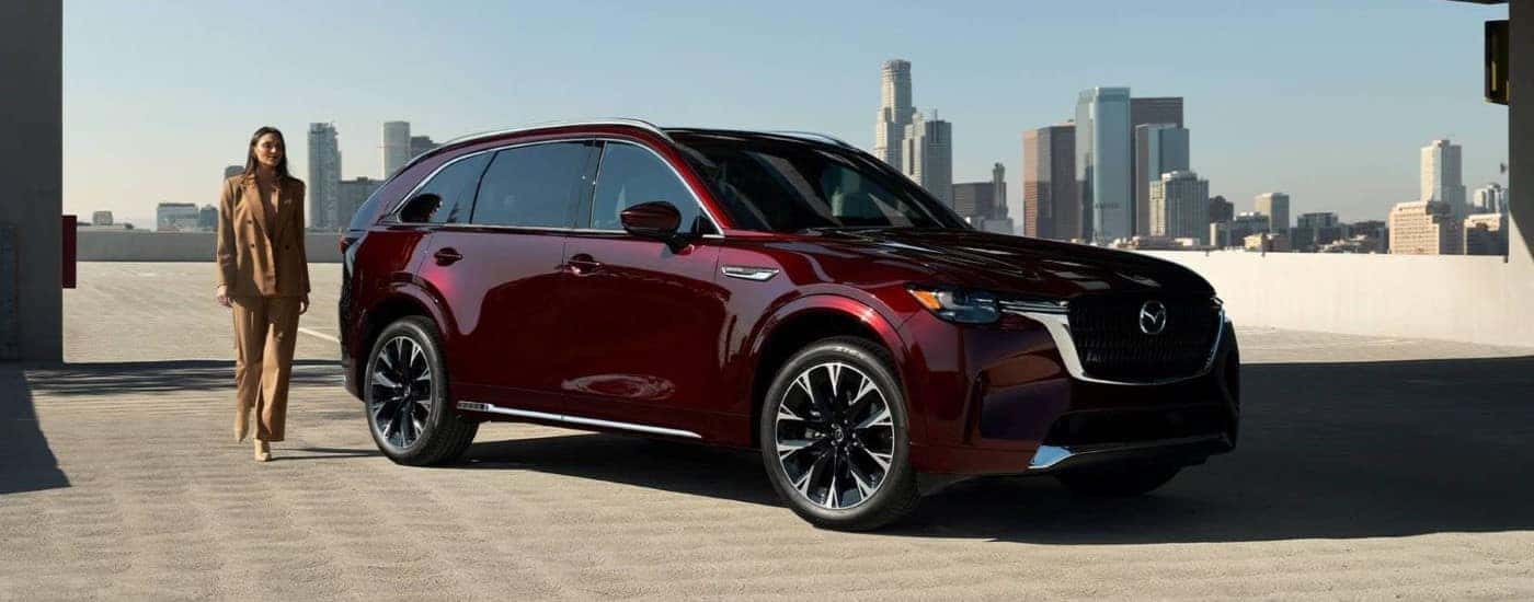 A maroon 2024 Mazda CX-90 parked near a city