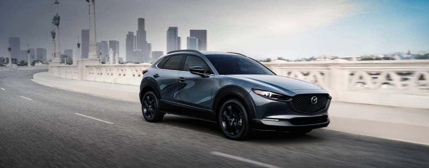 A blue 2025 Mazda CX-30 driving to a Mazda dealer near Rockville.