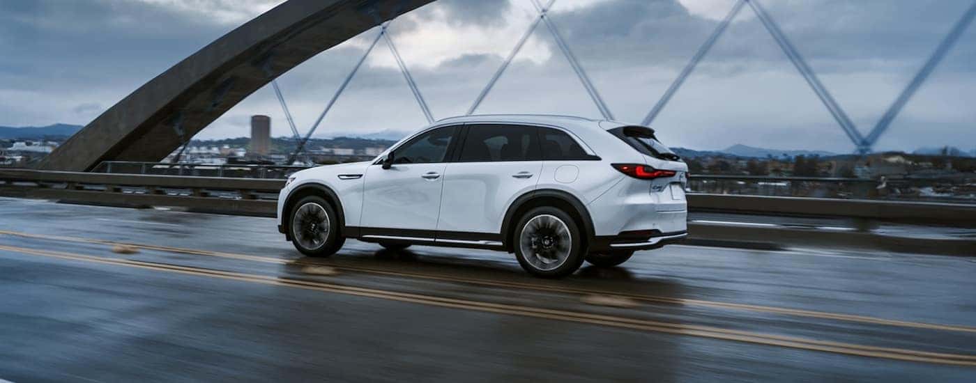 White 2026 Mazda CX-90 driving over a bridge.