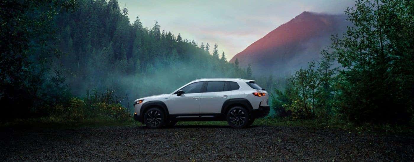 A white 2025 Mazda CX-50 parked off-road in the woods