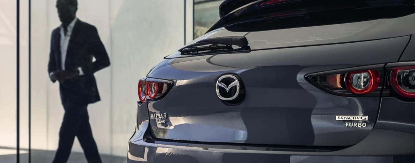 Rear end of a grey 2024 Mazda3 with a person walking past