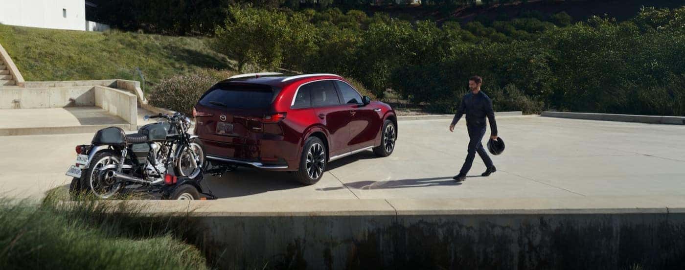 A red 2026 Mazda CX-90 tpwong a motorcycle on a trailer.