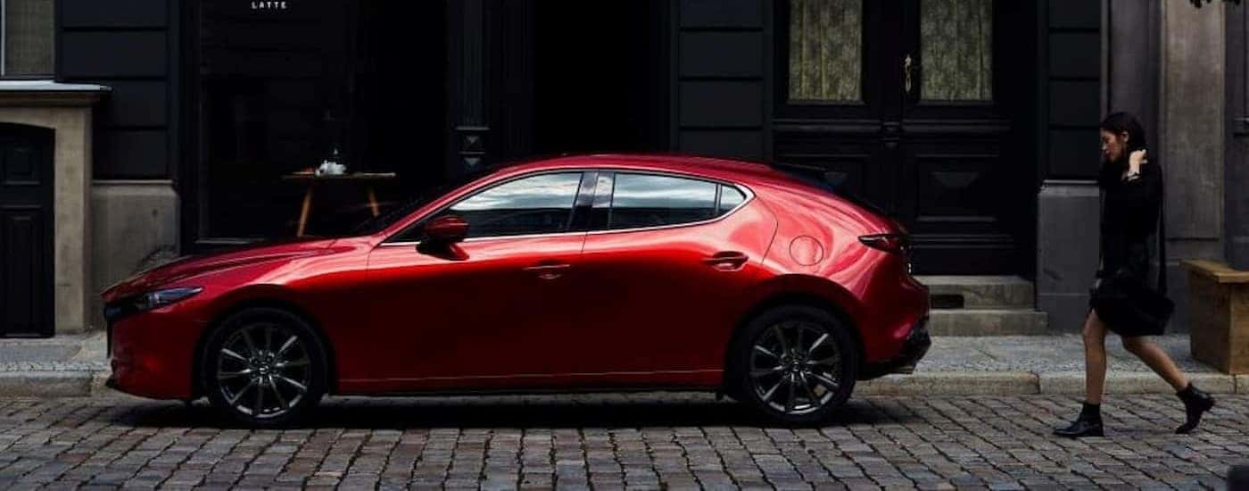 A red 2023 Mazda3 parked in a city.