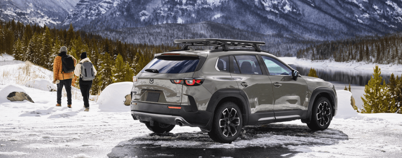 A couple walking next to their green 2026 Mazda CX-50