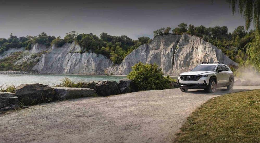 A white 2026 Mazda CX-50 driving near water.