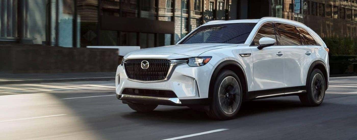 A white 2024 Mazda CX-90 driving in a city