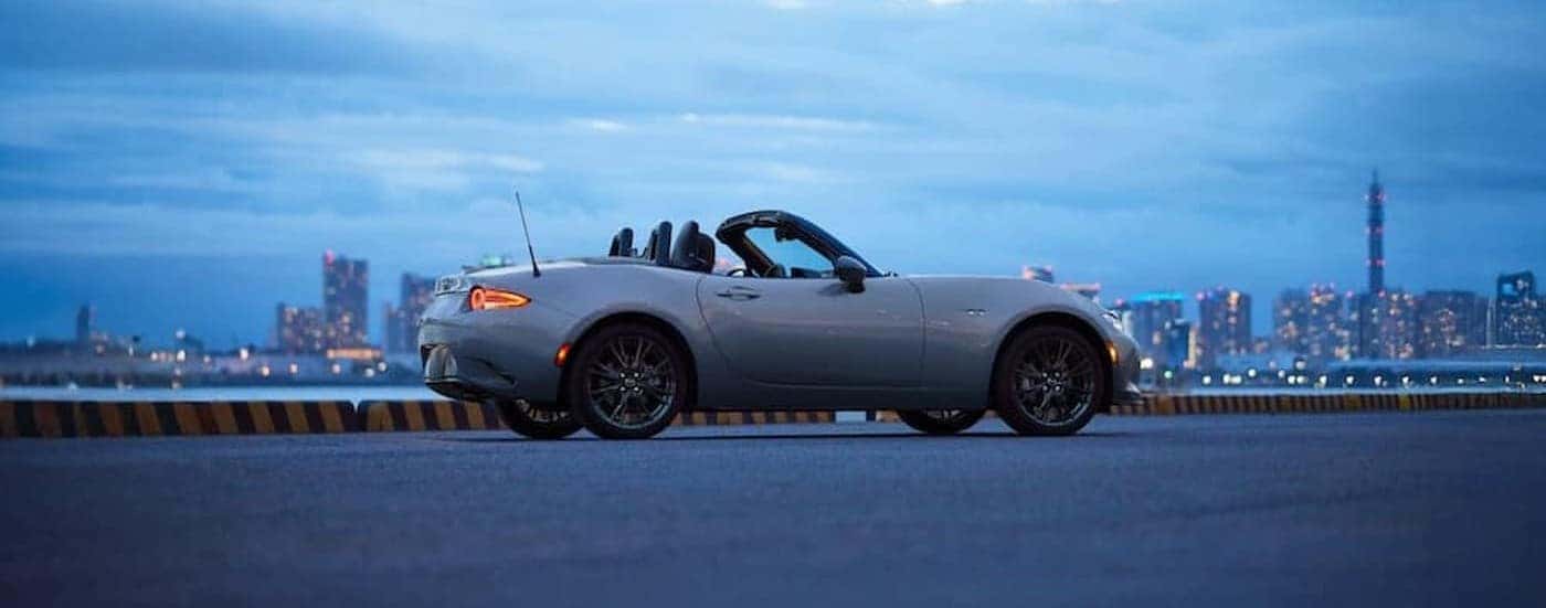A silver 2025 Mazda MX-5 Miata parked outdoors with its top down.