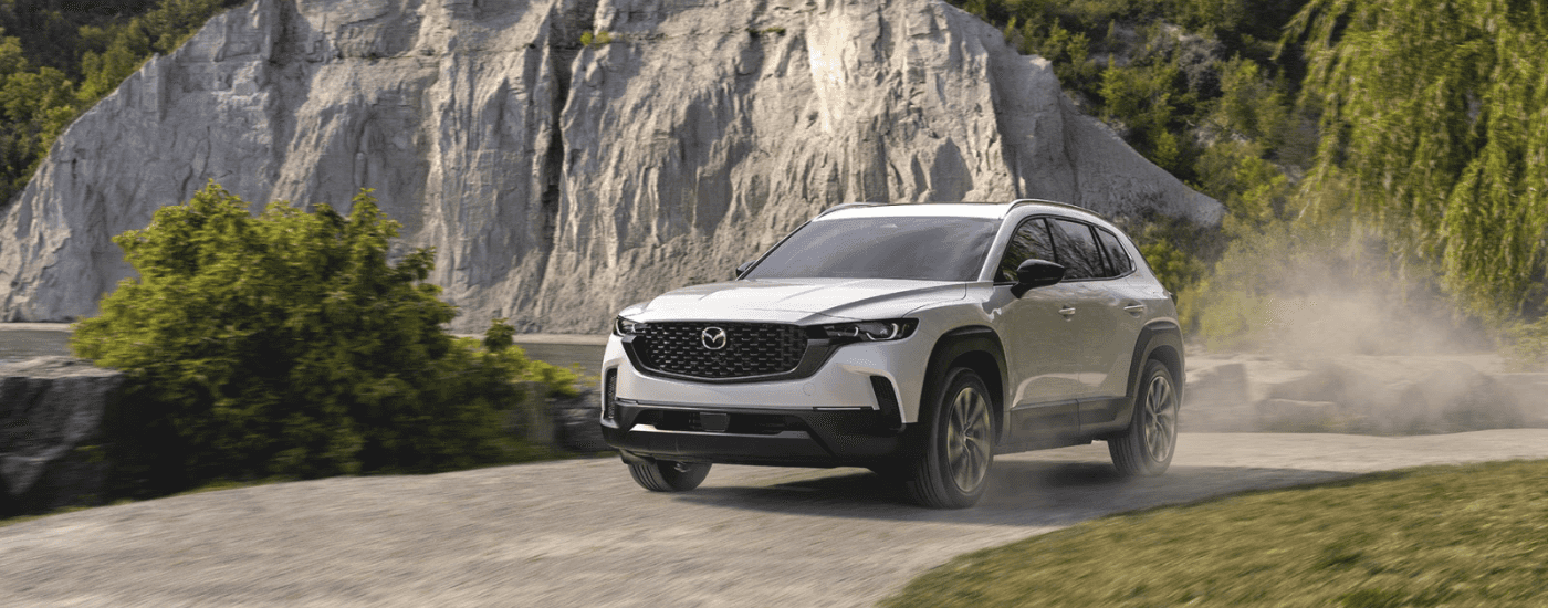 White 2026 Mazda CX-50 driving on a trail