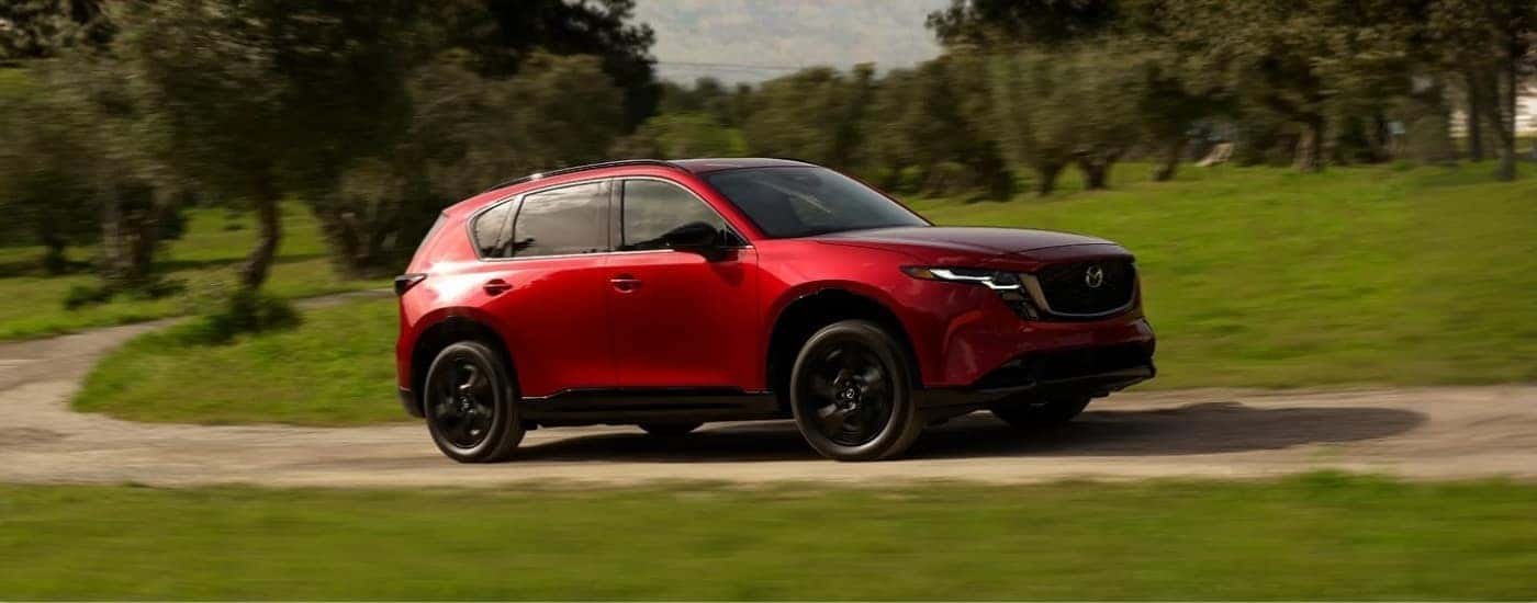 Red 2026 Mazda CX-5 driving past a field