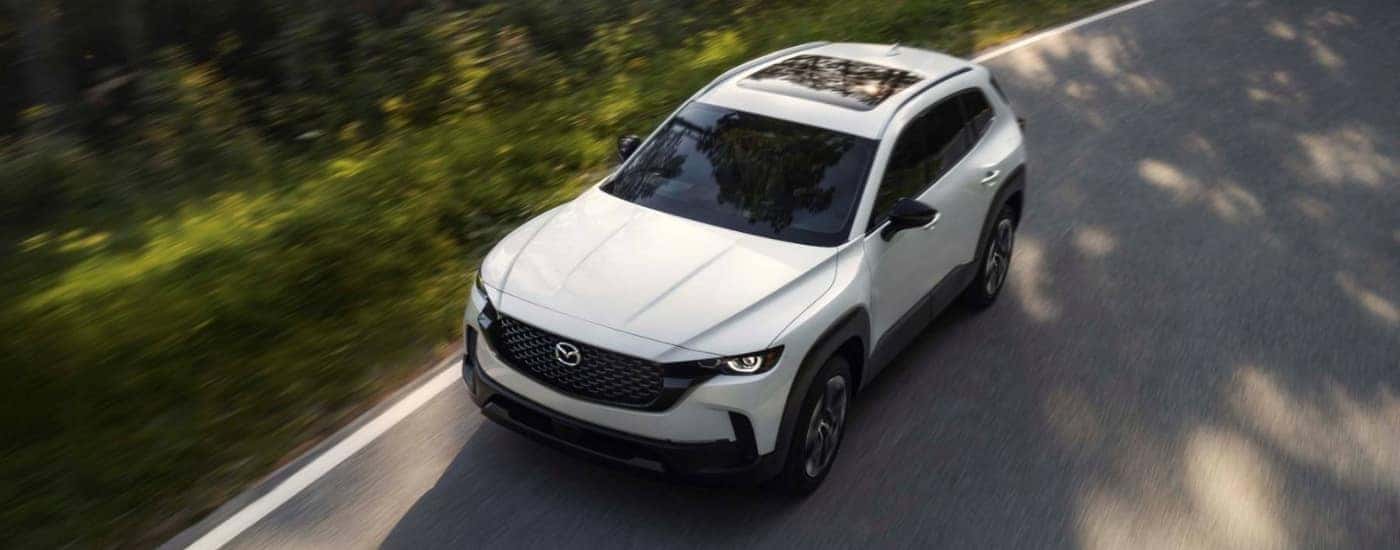 White 2026 Mazda CX-50 Hybrid driving on an open road