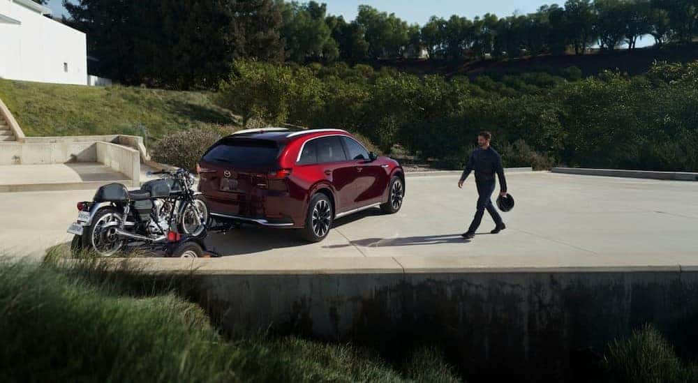 A red 2026 Mazda CX-90 towing a trailer.