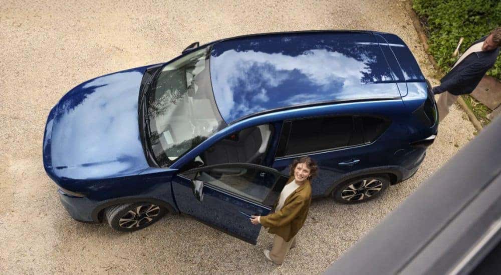 Top-down view of a woman entering a blue 2026 Mazda CX-5.