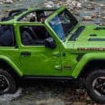Green 2019 Jeep Wrangler Rubicon driving off-road over rocky terrain