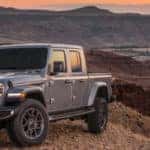Gray Jeep Gladiator parked in mountains overlooking a valley with a stream