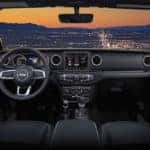 Front-seat view of 2019 Jeep Wrangler Sahara interior at dusk