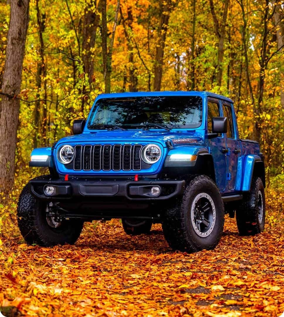 2026 Jeep Gladiator Rubicon in blue on a leaf-covered forest trail