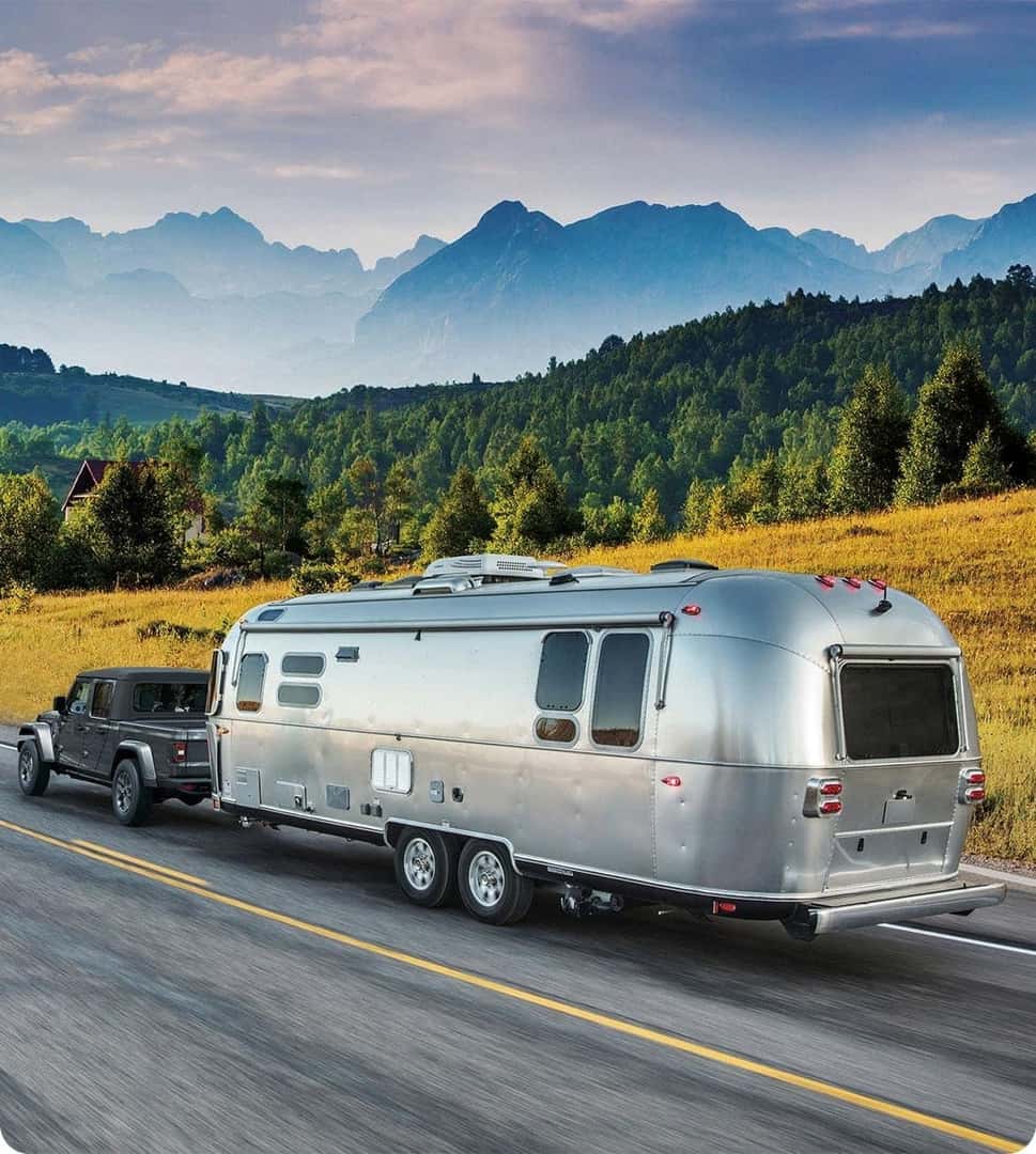 2026 Jeep Gladiator towing a travel trailer on a mountain highway