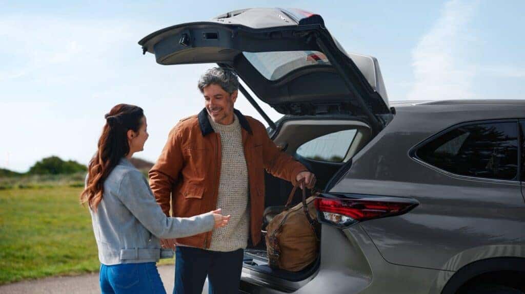 Husband and wife loading Toyota Highlander with luggage.