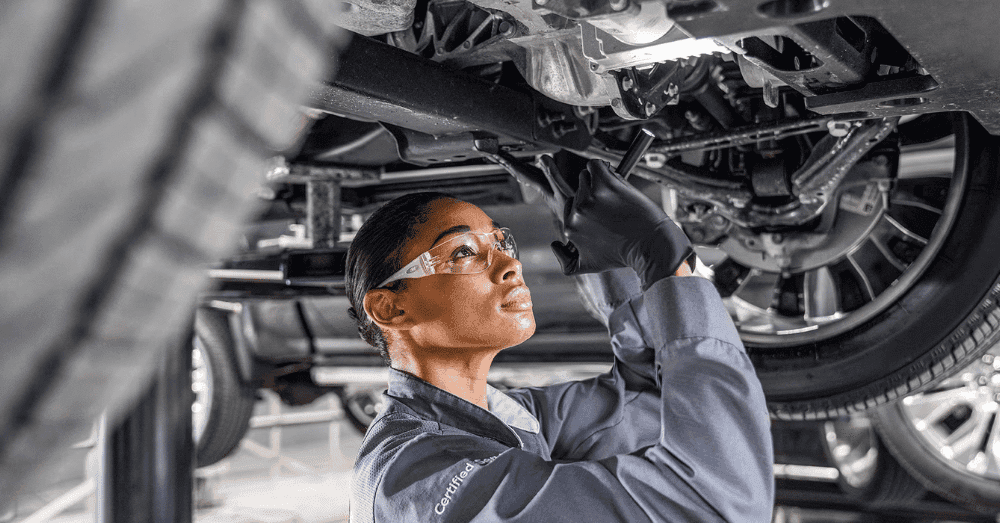 GMC Service Specials - woman GMC service technician checking undercarriage of GMC vehicle